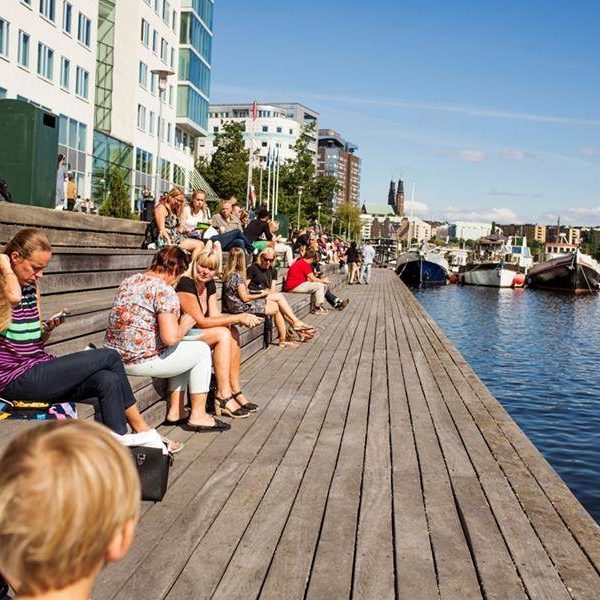 Människor solar på brygga vid vattnet